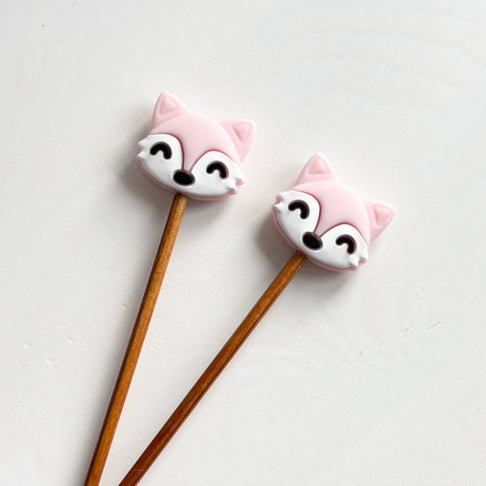 Vaaleanpunaiset kettu puikkostopparit. Auttavat pitämään silmukat puikoilla.