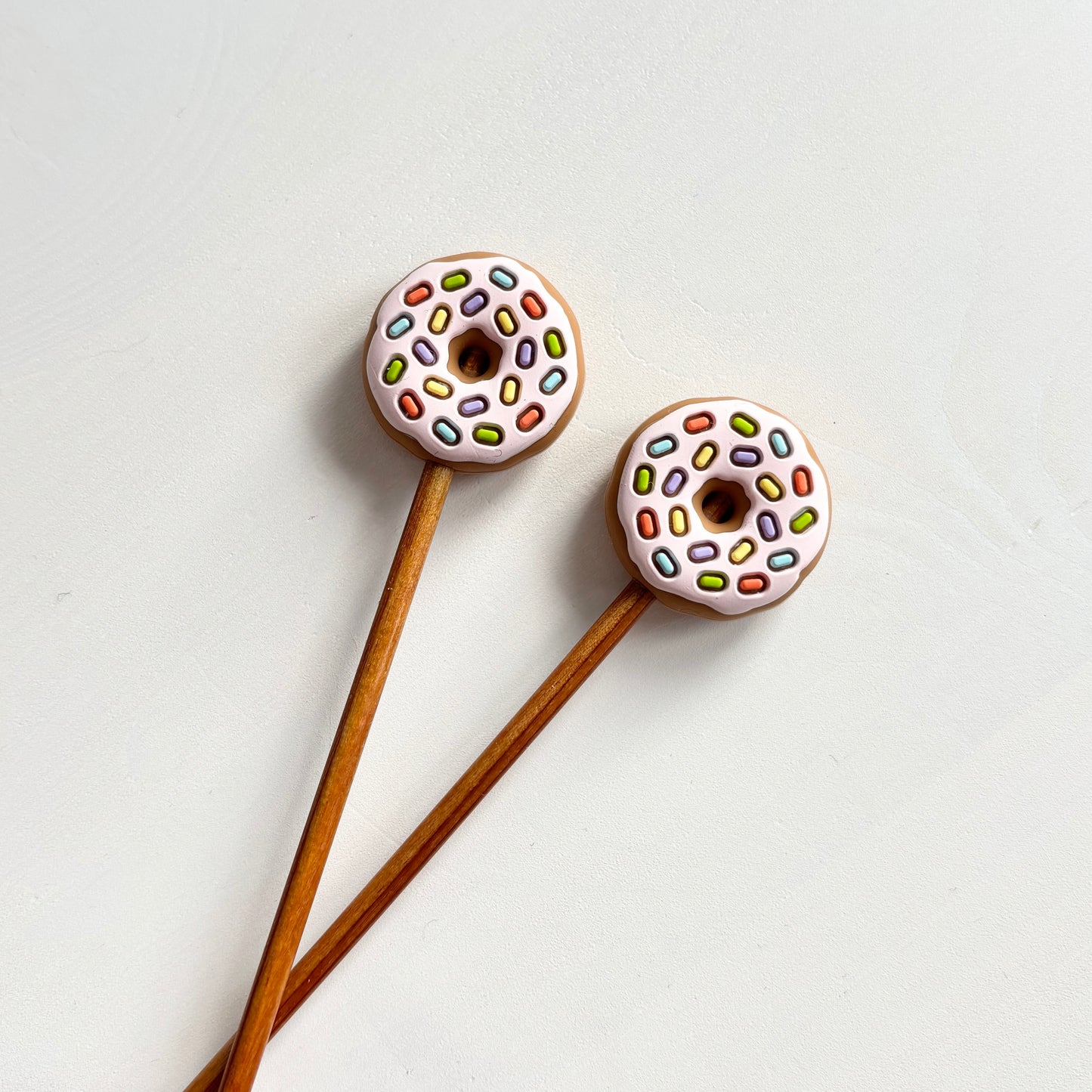 Ruskeat / vaaleanpunaiset donitsi puikkostopparit. Auttavat pitämään silmukat puikoilla.