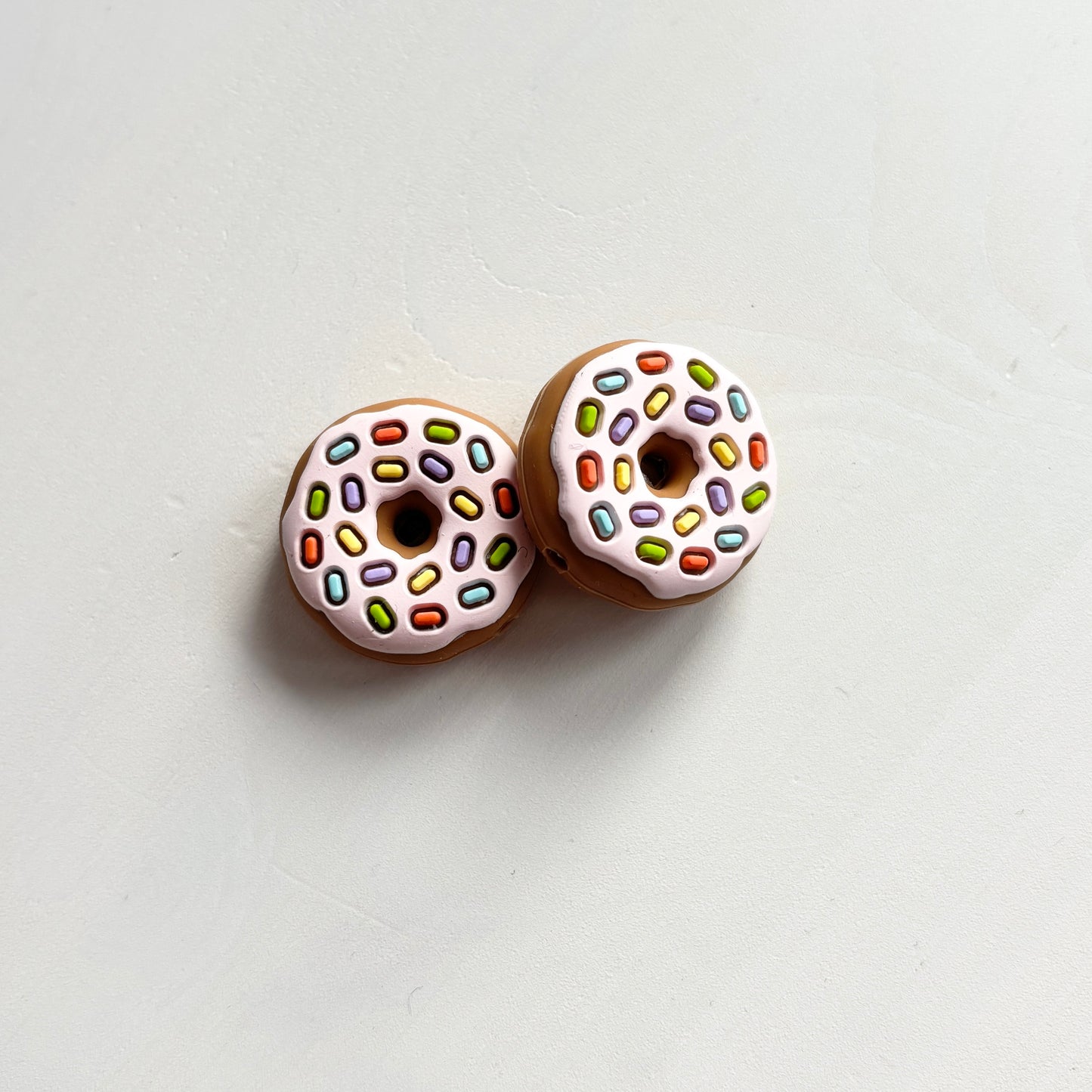 Ruskeat / vaaleanpunaiset donitsi puikkostopparit. Auttavat pitämään silmukat puikoilla.