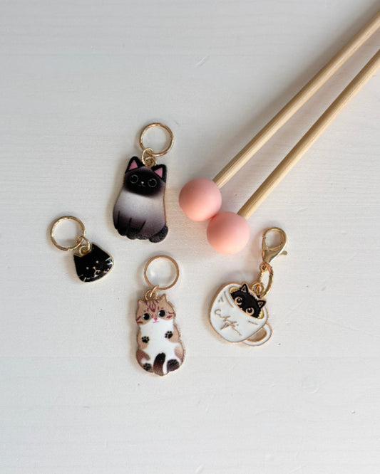 Kissa-aiheisia silmukkamerkkejä ja puikkostopparit neulomiseen.