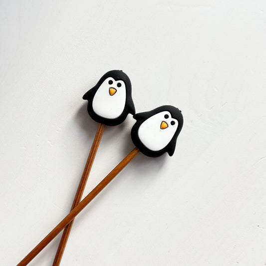 Mustat pingviini puikkostopparit. Auttavat pitämään silmukat puikoilla.